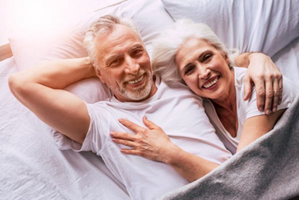 couple senior souriant dans un lit